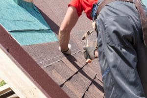 Roofer adding shingles to a roof