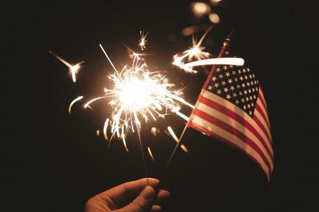 American Flag waving with sparkler in the background 