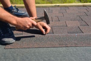 Roofer Installing Asphalt Shingles On House