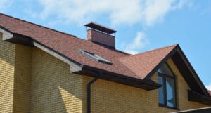 A Close-up Of A Brick House With A Brown Asphalt Shingled Roof,