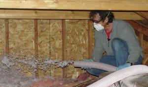 Technician spraying loose cellulose insulation into an attic