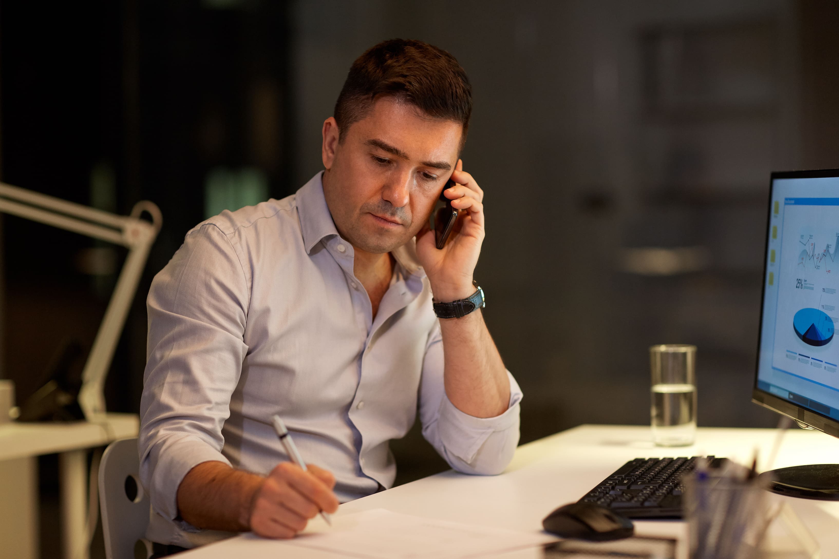 man on phone while also writing on a piece of paper