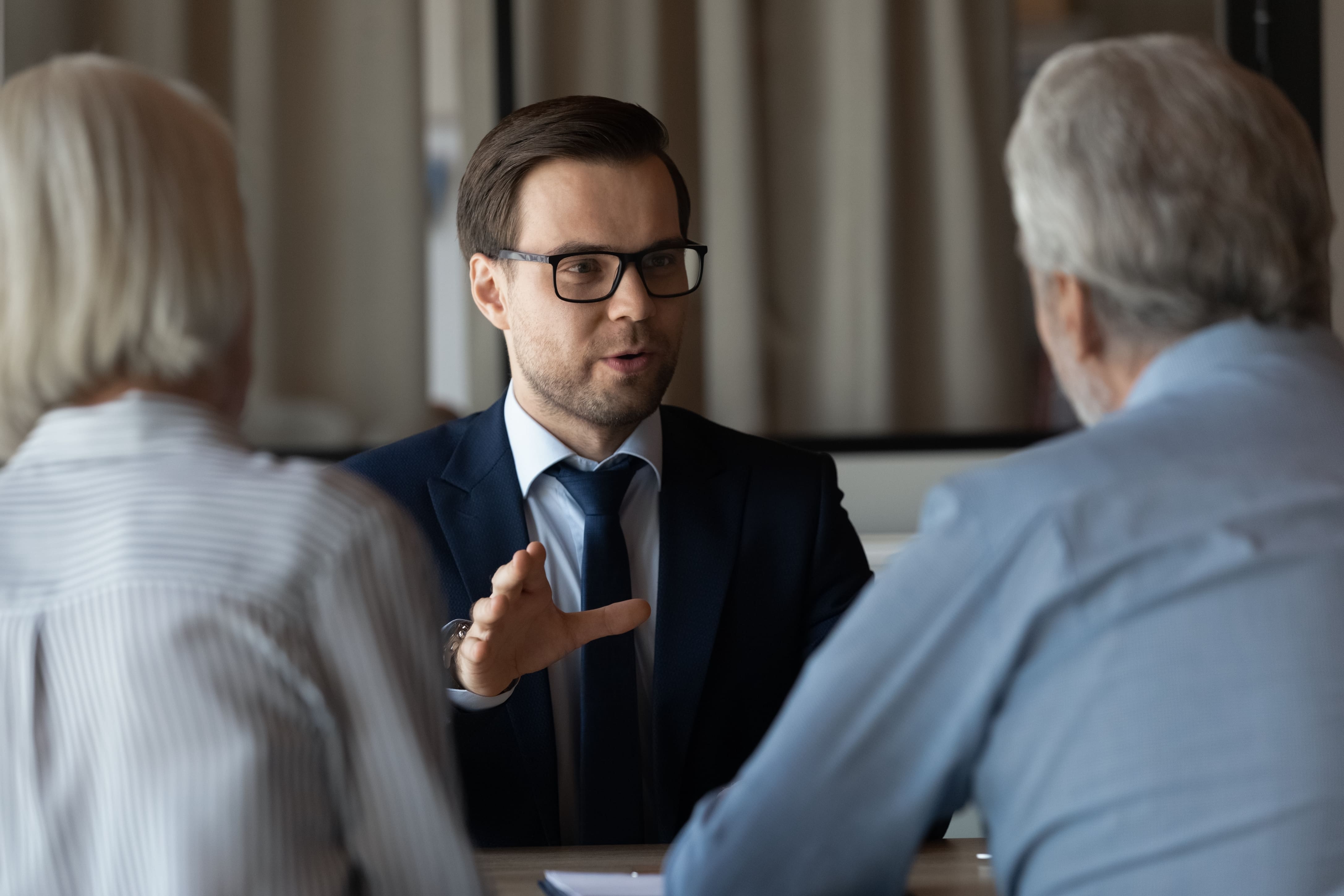 person in suit talking to an elderly couple