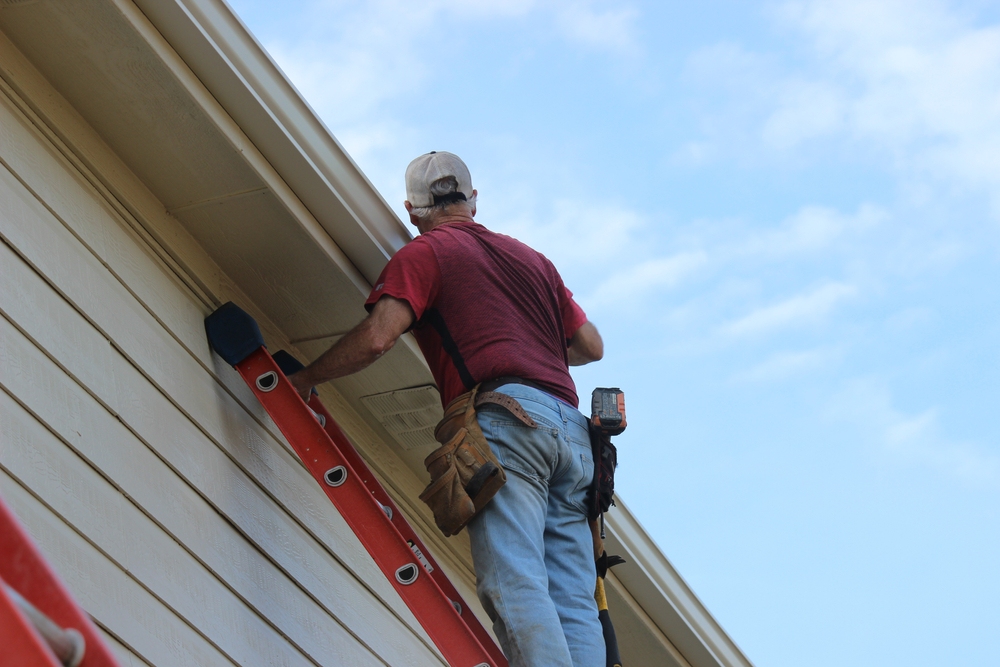 Contractor installing gutter system on a two story residential house in Albert Lea